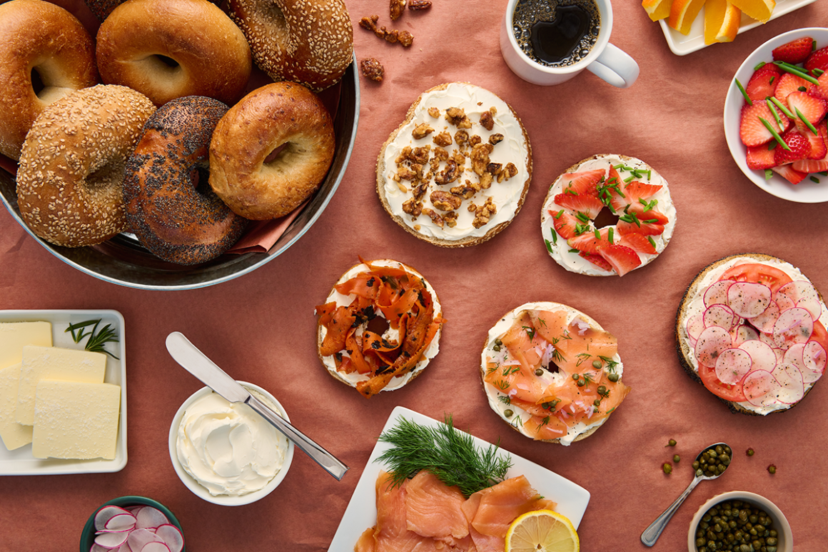 An assortment of bagels with cream cheese, lox, and different toppings on a table