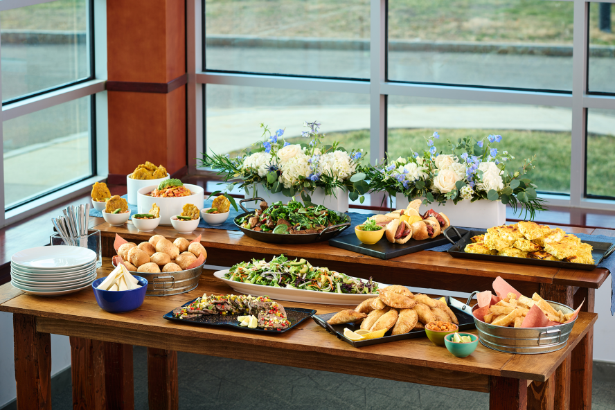 A buffet tablet setup featuring a wide range of meals to choose from and a white floral arrangement 