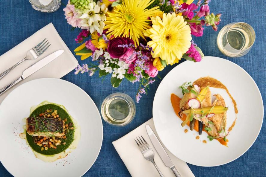 Two different salmon dishes on a table adorned with yellow flowers
