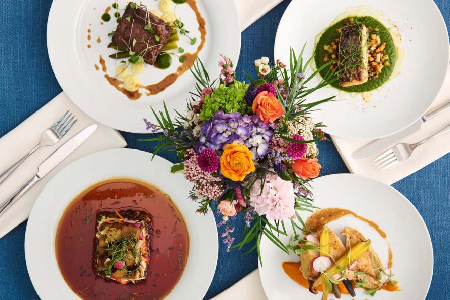 Various meals on a table adorned with a vase of flowers